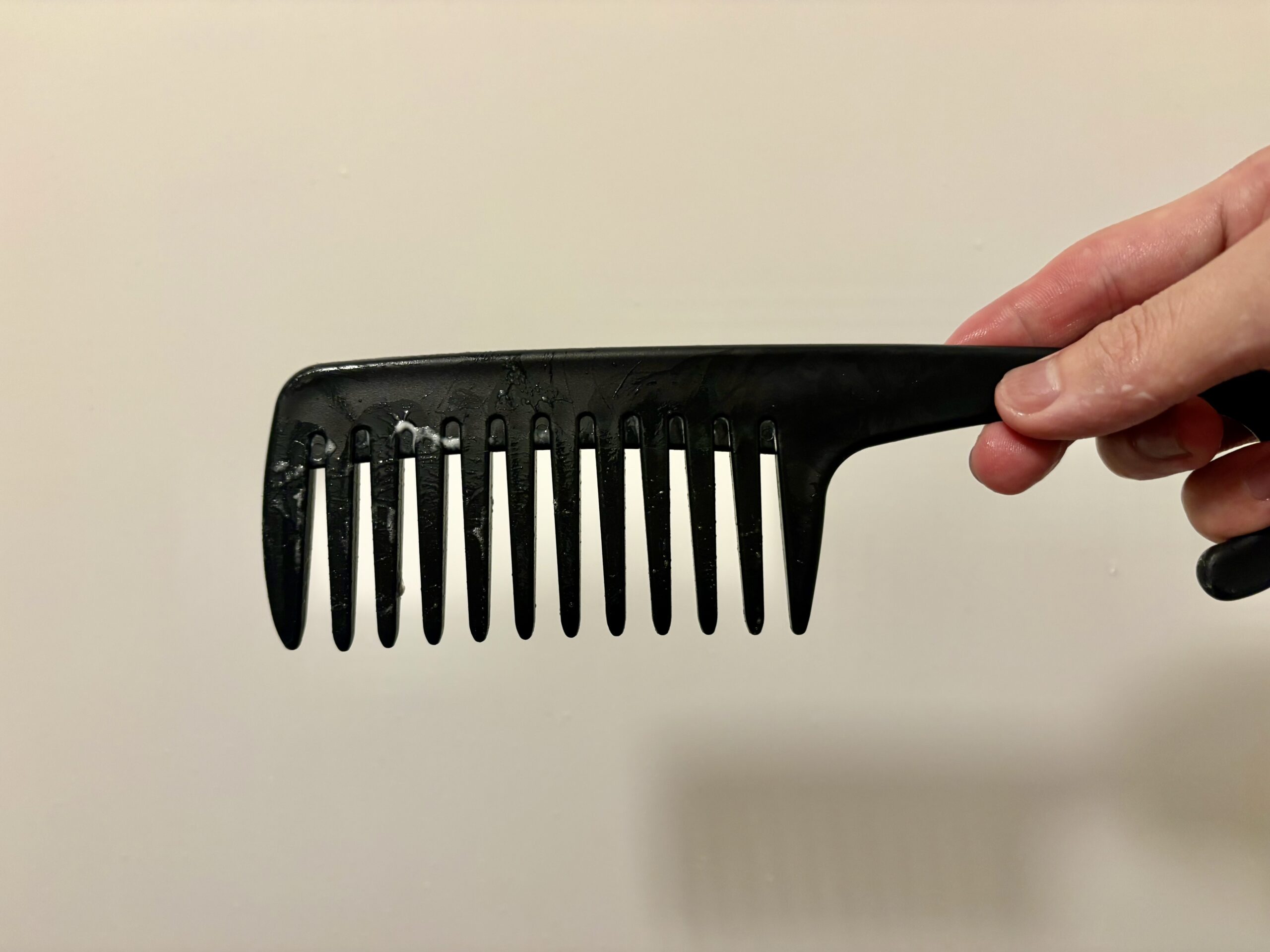 櫛で髪をとかしてトリートメントを均一にならすところ